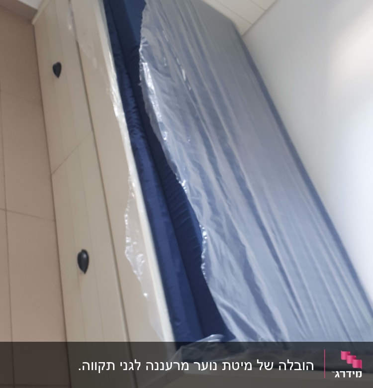 מזרן עטוף בניילון על מיטה לבנה